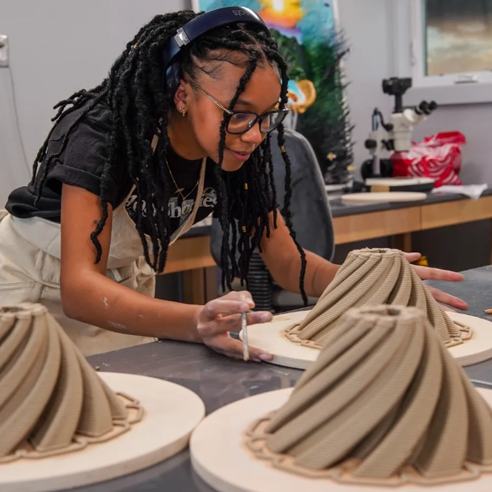 himb-splashweek-2025-coral-restoration A young woman moulding 3D coral reef in a lab setting.